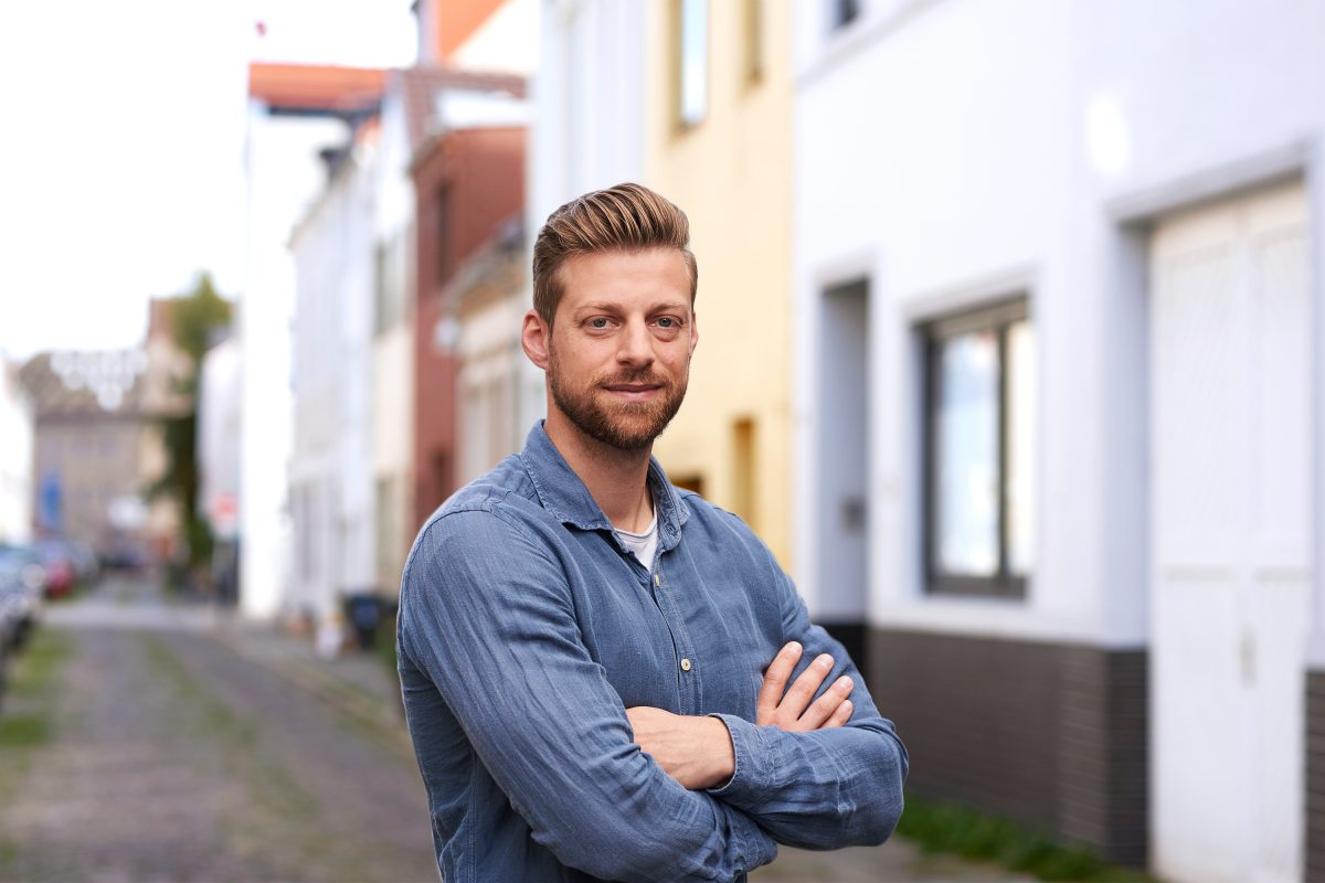 Ein lächelnder blonder Mann mit verschränkten Armen